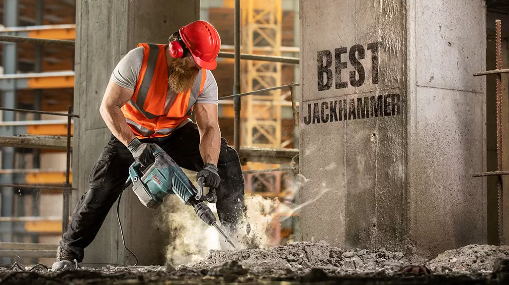Construction worker breaking concrete with heavy-duty jackhammer
