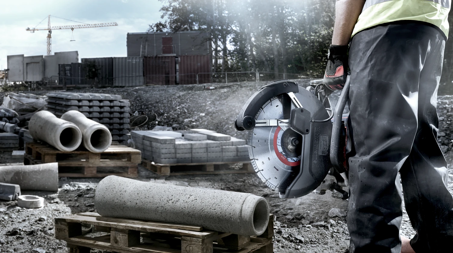 Professional using handheld concrete saw in construction site